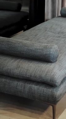 Dikey video. Gri kumaş bir kanepeye yakın çekim, tavan arası tarzı iç mekan, yavaş çekim. Modern iç tasarım. Yüksek kalite 4k görüntü