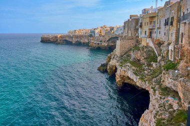 Polignano 'da güneşli bir sonbahar gününde Adriyatik Denizi üzerindeki dramatik uçurumlardaki evler...