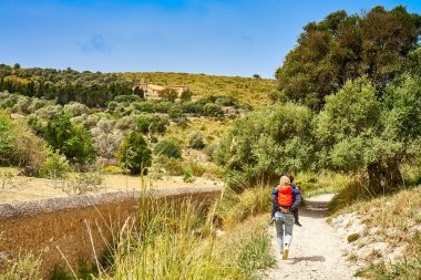 Sırtında 5 yaşındaki oğlunu tutan genç bayan Acros Ermita de Betlem Majorca İspanya 'dan geçiyor.