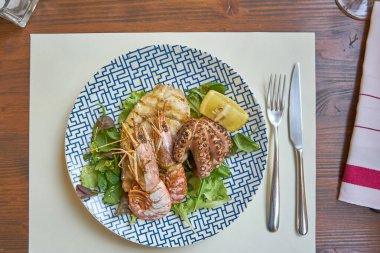 Karışık ızgara deniz ürünleri, Schrimps ton balığı bifteği, ahtapot ve modern giyinmiş bir masada servis edilen salata da dahil.