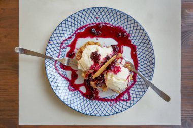 Yabani böğürtlenli tabakta servis edilen vanilyalı dondurma.