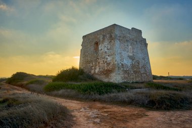 Torre Pozzelle harabeleri Renkli bir günbatımında antik bir sahil gözetleme kulesi Ostuni Puglia İtalya.