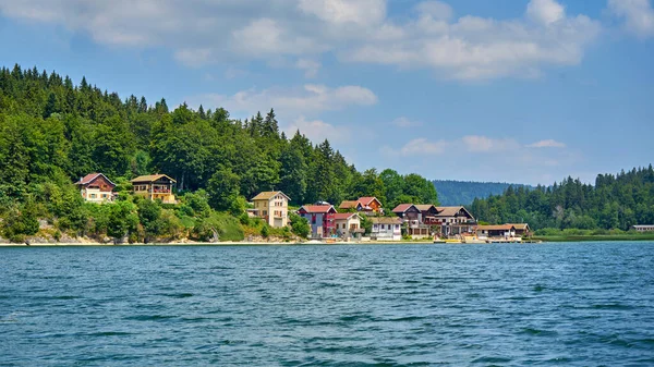 Saint Point Gölü 'nün sol kıyısında yer alan Port Titi A Little Hamlet Doubs France' ın panoramik görüntüsü, Port-Titi geçen yüzyılın başında bir grup balıkçı arkadaş tarafından inşa edildi.