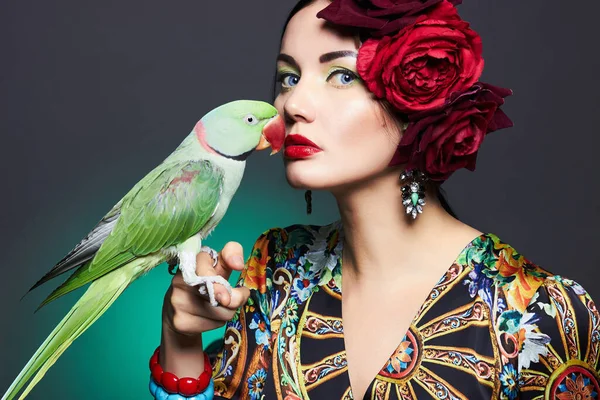 portrait of beautiful young woman with parrot and floral hat. colorful beauty girl with roses flowers on her head