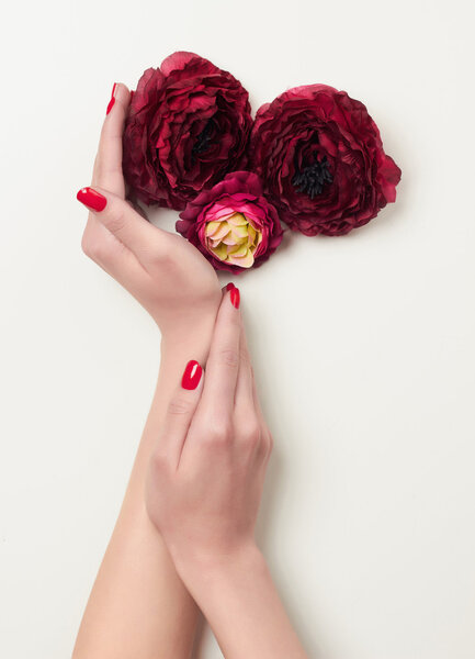 hands with red manicure and red flowers