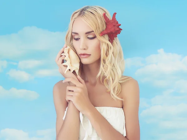 Beautiful blond girl listening a shell — Stock Photo, Image