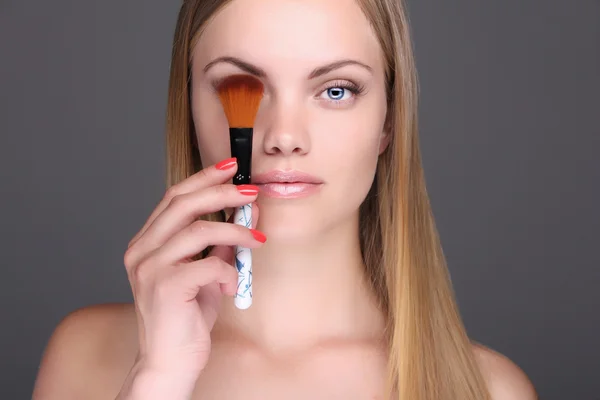 Junge blonde Frau mit Make-up-Pinsel — Stockfoto
