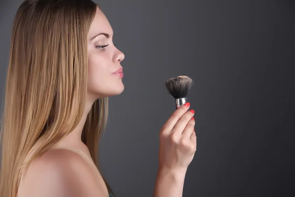Junge blonde Frau mit Make-up-Pinsel — Stockfoto