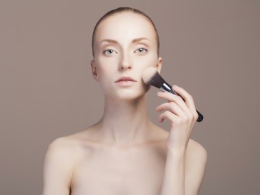 Makyaj yapan genç bir kadın.