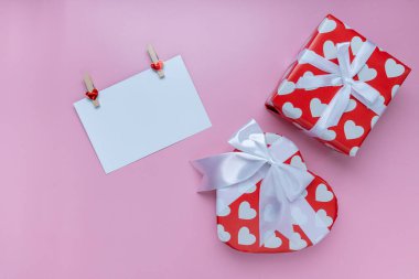 Hediye ya da hediye kutusu, küçük kalp ve pembe arka planda beyaz tebrik kartı. Pankart için. Sevgililer Günü konsepti. Üst görünüm, boşluk kopyala