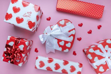 Kırmızı kalp şeklinde hediye ya da hediye kutusu, pembe arka planda mini kalp. Pankart için. Sevgililer Günü konsepti. Üst görünüm, boşluk kopyala