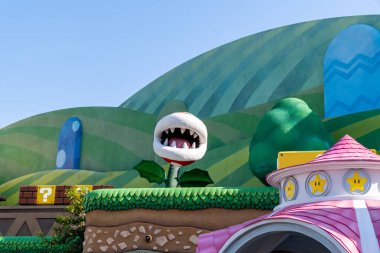 NOV 27 2025 Universal Studios Japan: Parlak güneşli bir günde video oyunlarından esinlenerek eğlence parkında dev bir bitkiyle renkli bahçe sahnesi