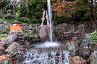 Su, bahçedeki kayalardan aşağı çağlar. Nehir boyunca küçük ışıklar parlıyor ve ağaçlar sonbahar boyunca renkli bir zemin sağlıyor. Sahnede bir tapınak görünüyor..