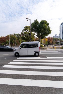 Japonya 'da gündüz vakti, Osaka, Japonya' da, 24 Kasım 2025 'te, yaya geçidinde trafik ışığı olan bir otomobil geçiyor.