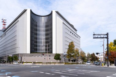 Bina, açık gökyüzü, Osaka, Japonya - 24 Kasım 2025 'te kentte trafik ve ağaçlarla dolu bir caddenin yakınında yer alıyor.