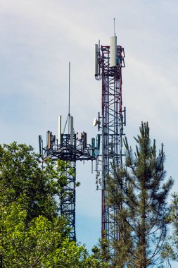 Arka planda ağaçlar ve gökyüzü arasındaki iki telekomünikasyon kulesinin görüntüsü