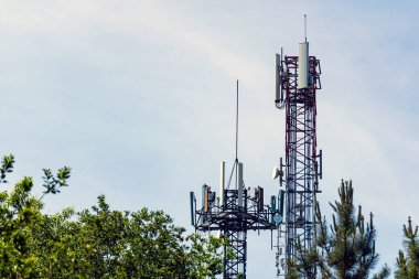 Arka planda ağaçlar ve gökyüzü arasındaki iki telekomünikasyon kulesinin görüntüsü