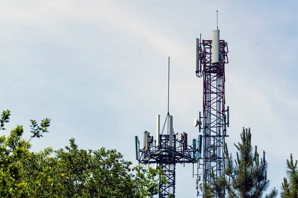 Arka planda ağaçlar ve gökyüzü arasındaki iki telekomünikasyon kulesinin görüntüsü