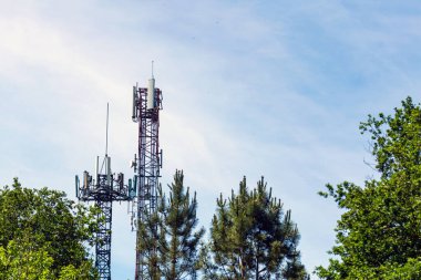 Arka planda ağaçlar ve gökyüzü arasındaki iki telekomünikasyon kulesinin görüntüsü