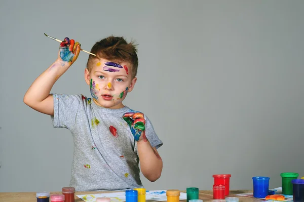 Милый маленький мальчик грязно играет с красками — стоковое фото