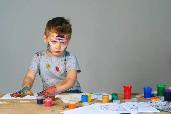 Милый маленький мальчик грязно играет с красками — стоковое фото