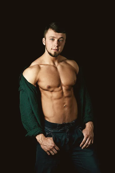 Young muscular man showing his body on a dark background — Stock Photo, Image