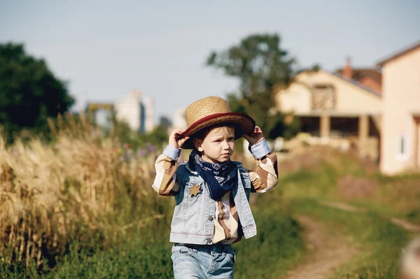 Маленький мальчик, одетый в западный стиль в поле, в стиле ретро — стоковое фото