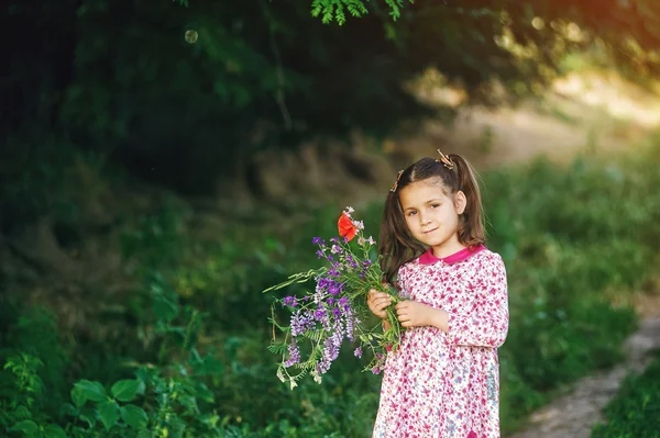 Bella bambina con fiori di campo nel parco — Foto Stock