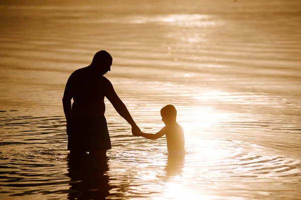 Père et fils jouant sur la plage au coucher du soleil . — Photo