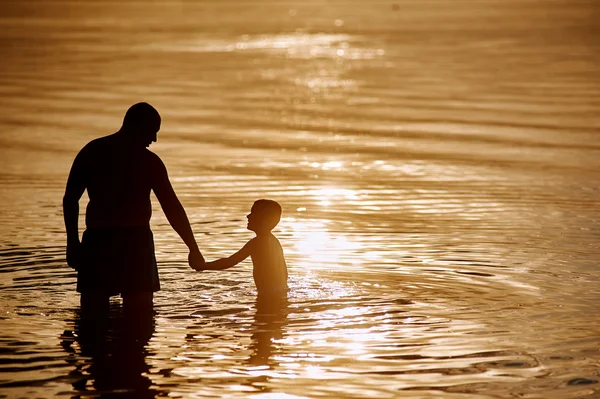 Père et fils jouant sur la plage au coucher du soleil . — Photo