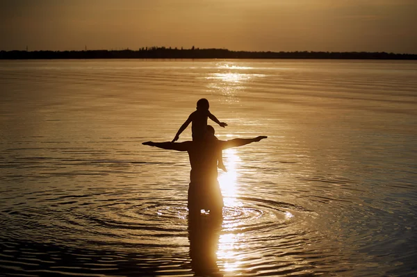 Père et fils jouant sur la plage au coucher du soleil . — Photo