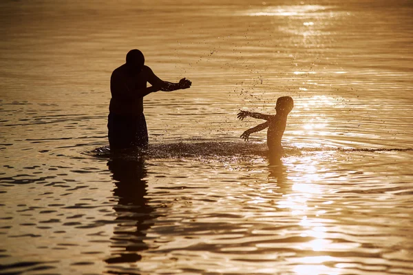 Père et fils jouant sur la plage au coucher du soleil . — Photo