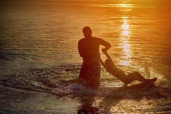 Père jouer avec les enfants dans l'eau pendant le coucher du soleil — Photo