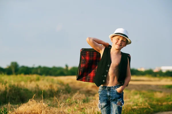 Menino elegante com mala vintage na estrada rural — Fotografia de Stock