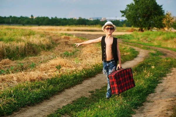 Garçon élégant avec valise vintage sur la route rurale — Photo