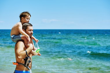 Baba ve oğul sualtı ekipman ile sahilde. Baba oğul yüzmeyi öğretiyor.