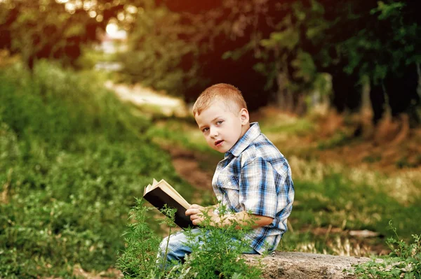 Jongetje lezen van een boek in het Park — Stockfoto
