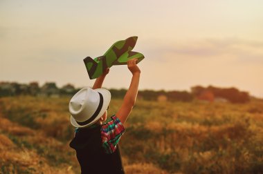 Gün batımı arka plan üzerinde oyuncak uçak ile oynayan mutlu çocuk