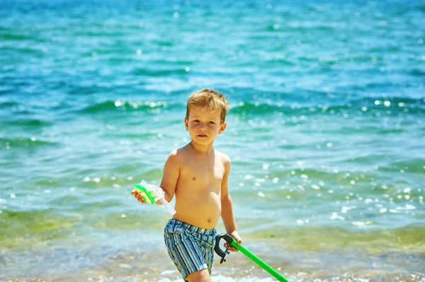 Мальчик позирует на пляже в снаряжении для подводного плавания. На фоне моря — стоковое фото
