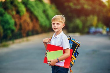 Elementary school student with books. Behind the boy's school backpack. clipart