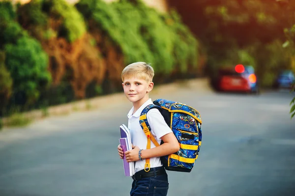 Elementary school student med böcker. Bakom pojkens skola ryggsäck. — Stockfoto