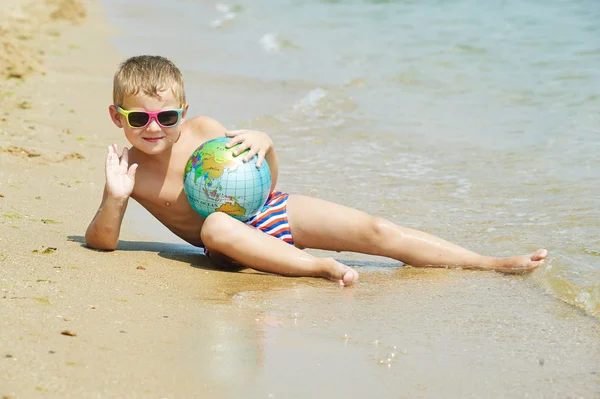 Chłopak na plaży z piłką kuli ziemskiej — Zdjęcie stockowe