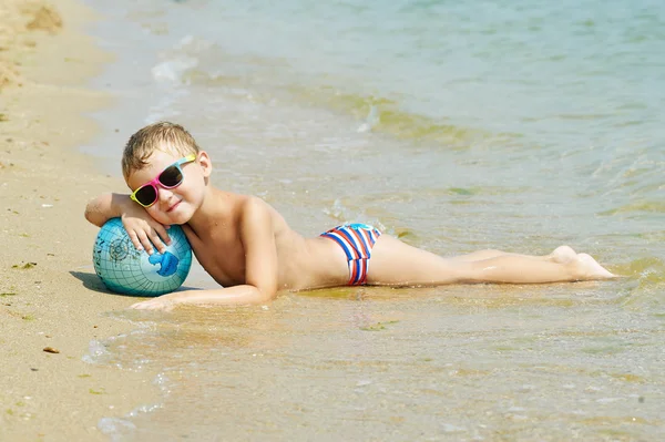 Chłopak na plaży z piłką kuli ziemskiej — Zdjęcie stockowe