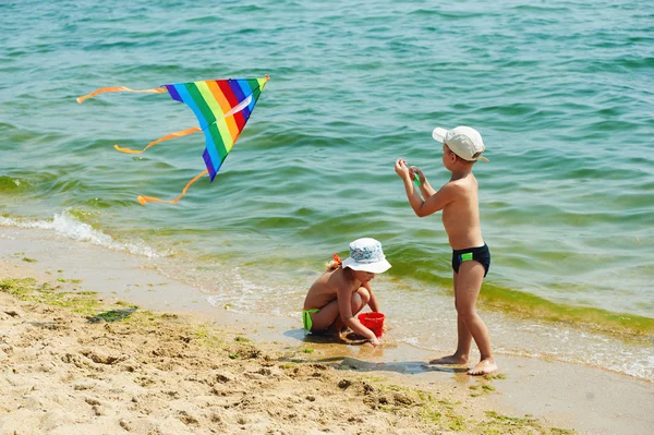 Kinder am Strand spielen mit einem Drachen — Stockfoto
