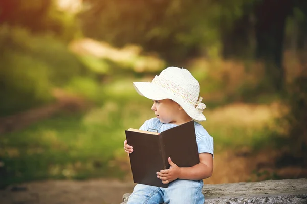 Little girl with book in the Park at sunset . Preschool education — Stock Photo, Image