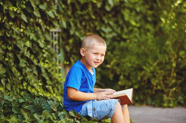 Jongen zitten met een boek in de tuin — Stockfoto