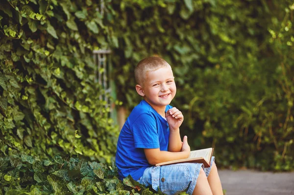 Мальчик сидит с книгой во дворе — стоковое фото