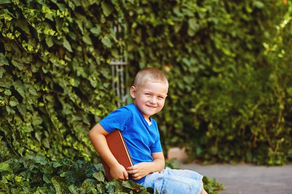 Junge sitzt mit Buch im Hof — Stockfoto