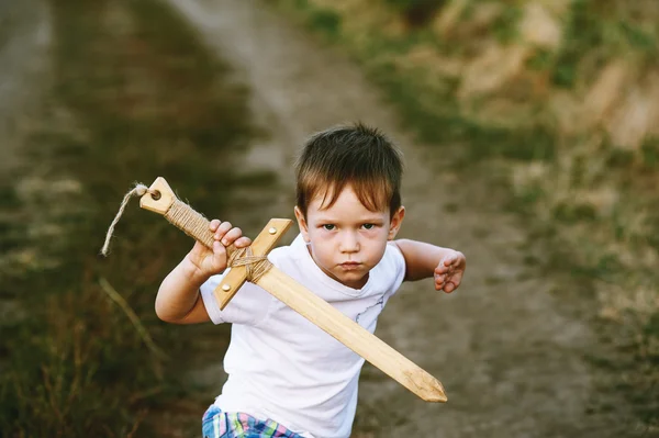 Мальчик играет с деревянным мечом — стоковое фото