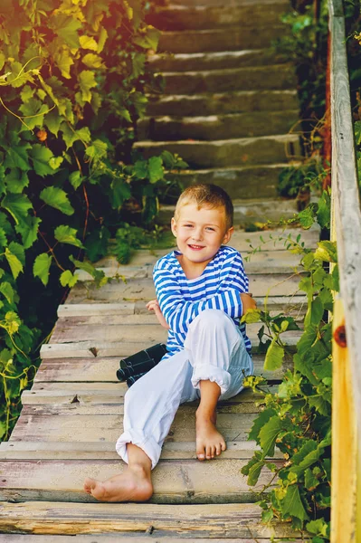 Schöner schwuler Junge, der auf einer Holztreppe posiert. gekleidet im nautischen Stil . — Stockfoto